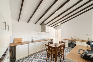A modern kitchen with white cabinets, a wooden countertop, and a dining area with a table and chairs.