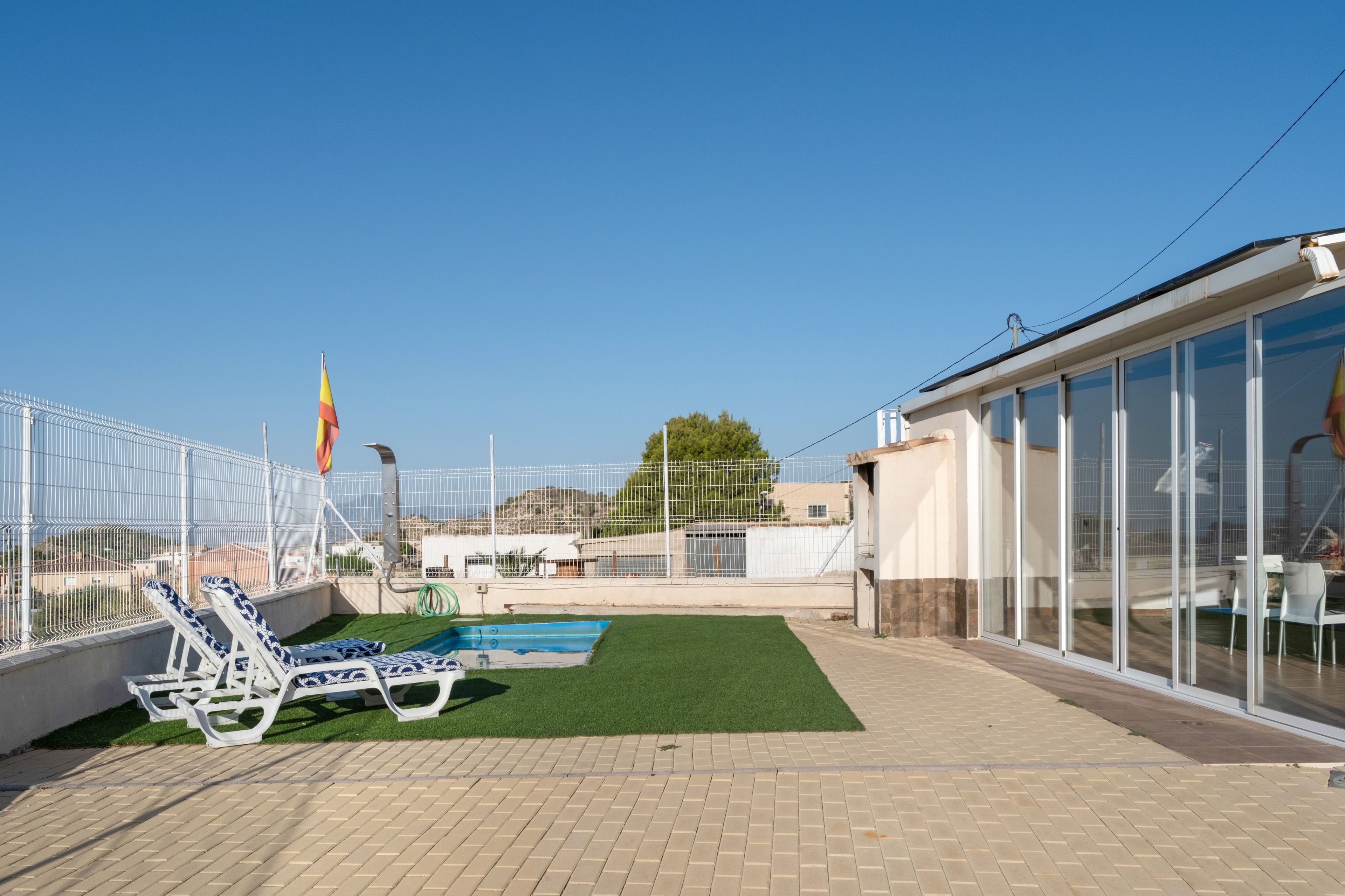 Un área de piscina en la azotea con sillones de descanso y una bandera.