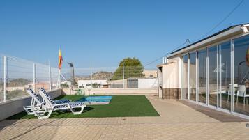 Un área de piscina en la azotea con sillones de descanso y una bandera.