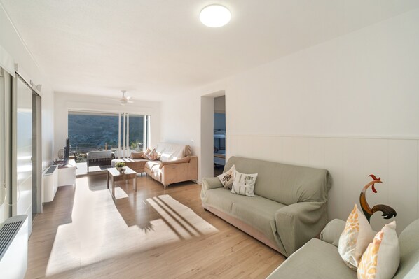 A modern living room with a sofa, a coffee table, and a dining area with chairs.
