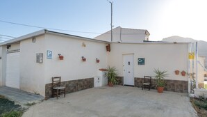 A building with a parking sign, a door, and a small garden area with potted plants. - Chalet 'Los Majales' with Private Pool, Wi-Fi, and Air Conditioning (Molina de Segura)