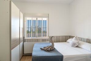 Un dormitorio con cama, ventana con rejas y radiador.