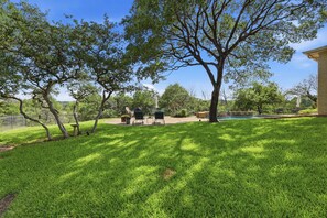 Ein Garten mit Swimmingpool, Terrasse und Rasenfläche.