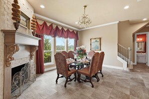 A dining room with a fireplace, a chandelier, and a view of the outdoors. - Spacious Ranch Retreat w/ Pool & Outdoor Living (Fort Worth)