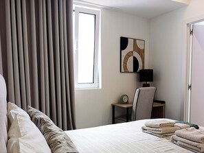 A hotel room with a bed, a desk, a chair, and a window with curtains. - Seascape Penthouse - Wake Up to the Atlantic | Oceanfront Penthouse (Funchal)