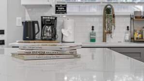Un plan de travail de cuisine avec une pile de livres de recettes et une machine à café.