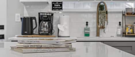 A kitchen counter with a stack of cookbooks and a coffee maker.