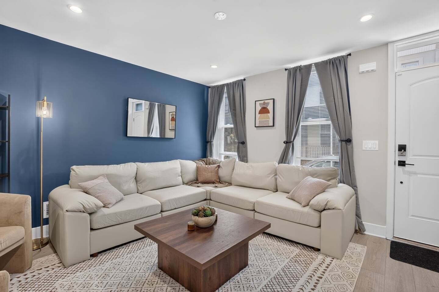 A modern living room with a sectional sofa, a coffee table, and a floor lamp.