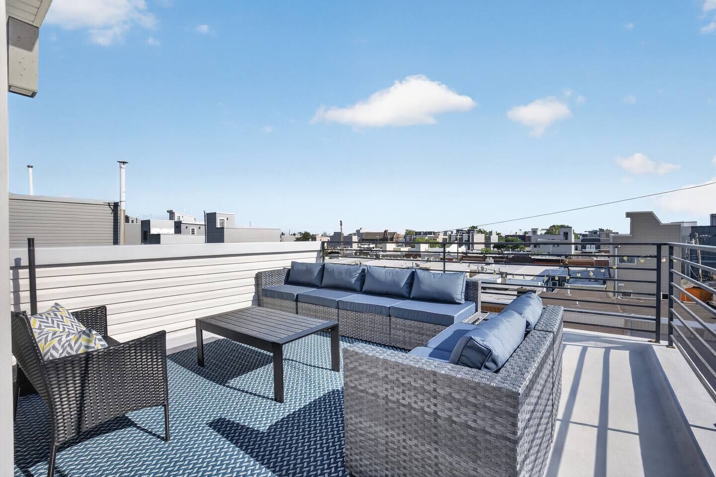 Een terras op het dak met een zithoek, een tafel en een stoel.