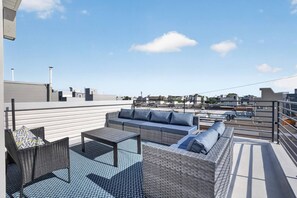 A rooftop terrace with a sofa set, a table, and a chair.