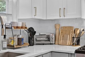 A kitchen with white cabinets, a toaster, wooden cutting boards, and a spice rack.