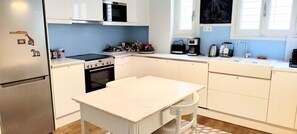 Eine Küche mit weißen Schränken, einem Kühlschrank, einem Herd und einer Mikrowelle.