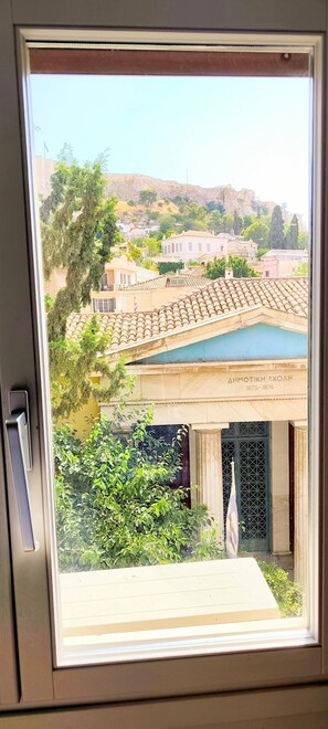 Blick aus dem Fenster auf ein Gebäude mit einem Ziegeldach, einer Flagge und einer Gedenktafel mit Jahreszahlen.