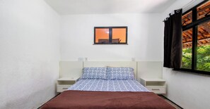 A small, single-bed room with a window, a nightstand, and a bedside table. - Flat em Aquiraz a 500m do Beach Park com Vista Mar (Aquiraz)