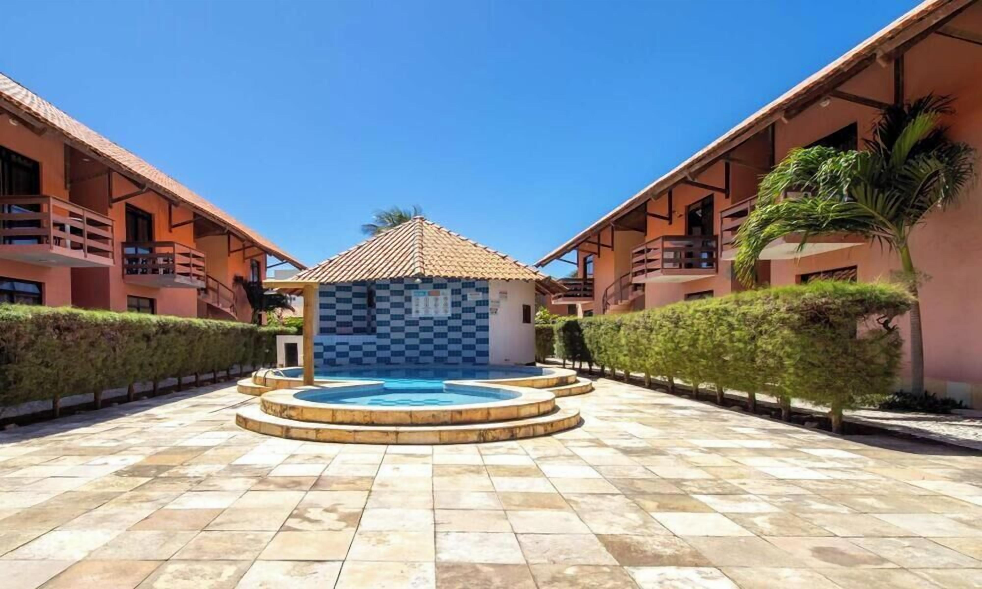 Ein Innenhof mit einem zentralen Pool, umgeben von zweistöckigen Gebäuden mit Balkonen.