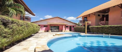 A swimming pool with a checkered pattern, a building with a pink facade, and a clear blue sky.