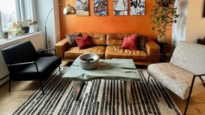 Una sala de estar moderna con un sofá, sillones, una mesita de centro y una planta colgante.