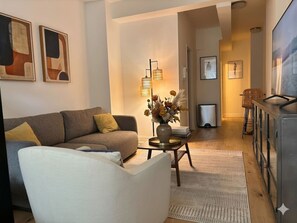 A modern living room with a sofa, a coffee table with a vase, and a television on a cabinet. - West Village Wonder - Amazing Location (New York)