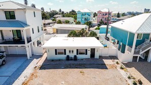 A multi-story residential building with a flat roof, a covered parking area, and a clear view of the surrounding neighborhood. - Sunshine Nook - 1/2 Block to the Beach (Fort Myers Beach)