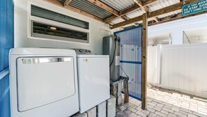 A laundry area with two washing machines, a water heater, and a blue gate. - Sunshine Nook - 1/2 Block to the Beach (Fort Myers Beach)