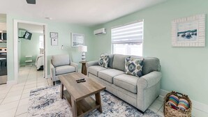 Una sala de estar con sofá, sillón, mesa de centro y ventilador de techo.