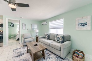 Ein Wohnzimmer mit einer Couch, einem Sessel, einem Couchtisch und einem Deckenventilator.