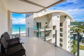 Ein moderner Hotelbalkon mit Meerblick, ausgestattet mit einer Sitzecke und einem Glasgeländer.