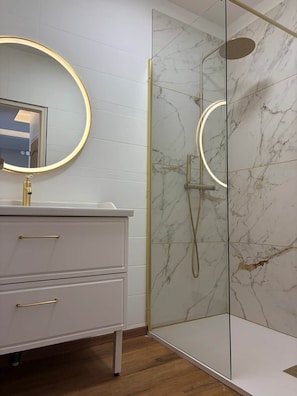 A modern bathroom with a glass-enclosed shower, a white vanity with gold handles, and a round mirror with a gold frame. - Le Balcon de Sarlat * Private parking & Town center 25 meters away (Sarlat-la-Canéda)