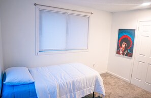 A bedroom with a bed, a window with blinds, a door, and a poster on the wall. - Cozy 2-bedroom house in charming Niles with AC (Niles)