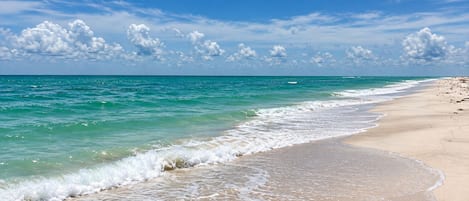 Una spiaggia con acque cristalline turchesi, onde tranquille e una riva sabbiosa.