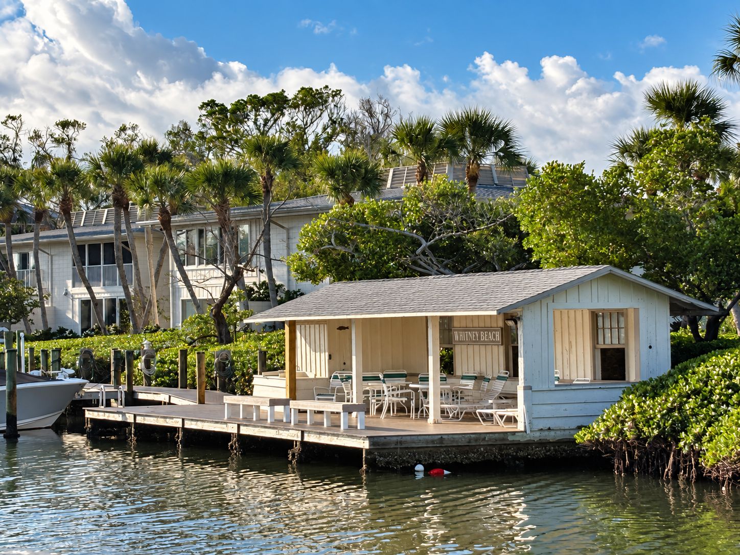 A waterfront property with a dock, lounge chairs, and a small building labeled 'Whitney Beach.'