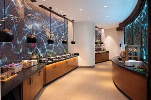 A modern hotel lobby with a curved reception desk, a wall with a mosaic design, and pendant lighting. - 1 Bedroom Villa at Westin Nanea Ocean Resort (Lahaina)