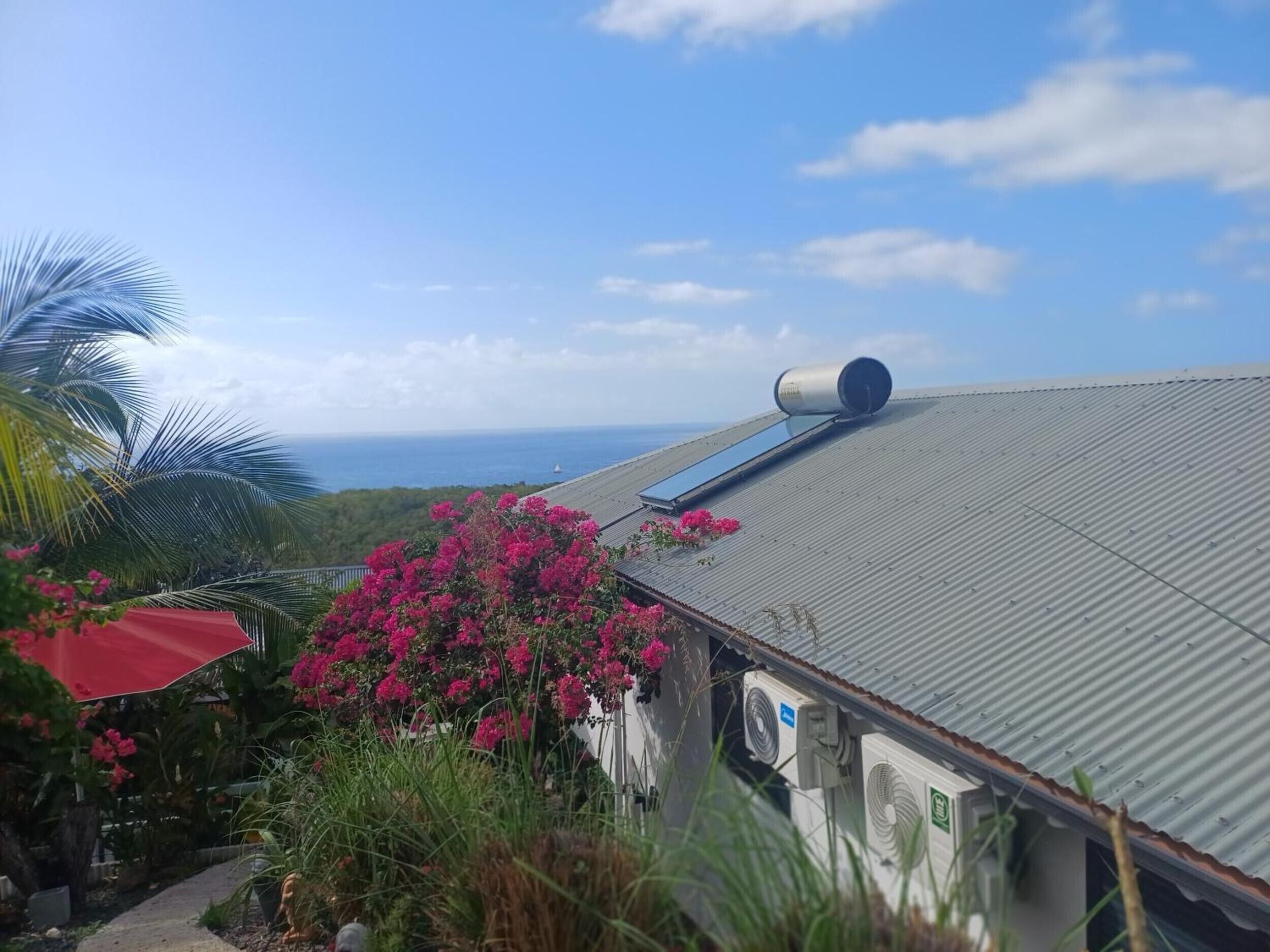 Um edifício com telhado de metal, um objeto cilíndrico grande no telhado e vista para o oceano.