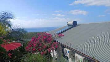 Um edifício com telhado de metal, um objeto cilíndrico grande no telhado e vista para o oceano.