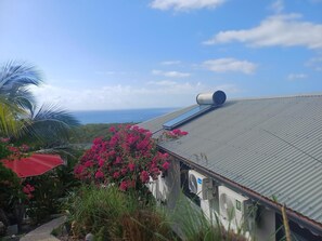 A building with a metal roof, a large cylindrical object on the roof, and a view of the ocean.