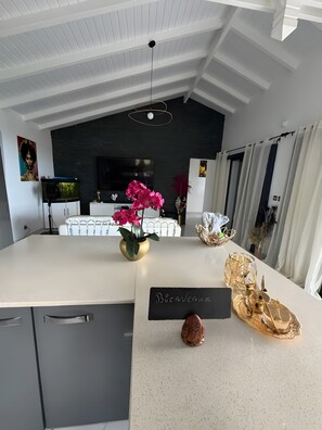 Une cuisine moderne avec un îlot central, un panneau d’affichage noir et des éléments décoratifs.