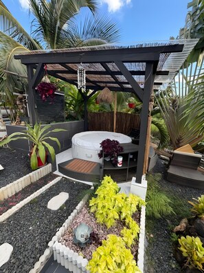 Un jardín con pérgola, asientos y diversas plantas.