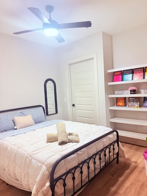 A bedroom with a bed, a ceiling fan, a door, and a shelf with books. - Cozy Stylish Dallas  1-bedroom apartment with AC in excellent Dallas location (Dallas)