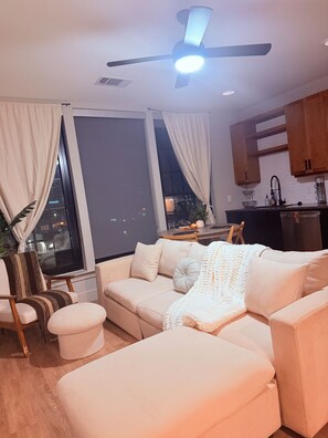 A modern living room with a sofa, ottoman, and a ceiling fan. - Cozy Stylish Dallas  1-bedroom apartment with AC in excellent Dallas location (Dallas)