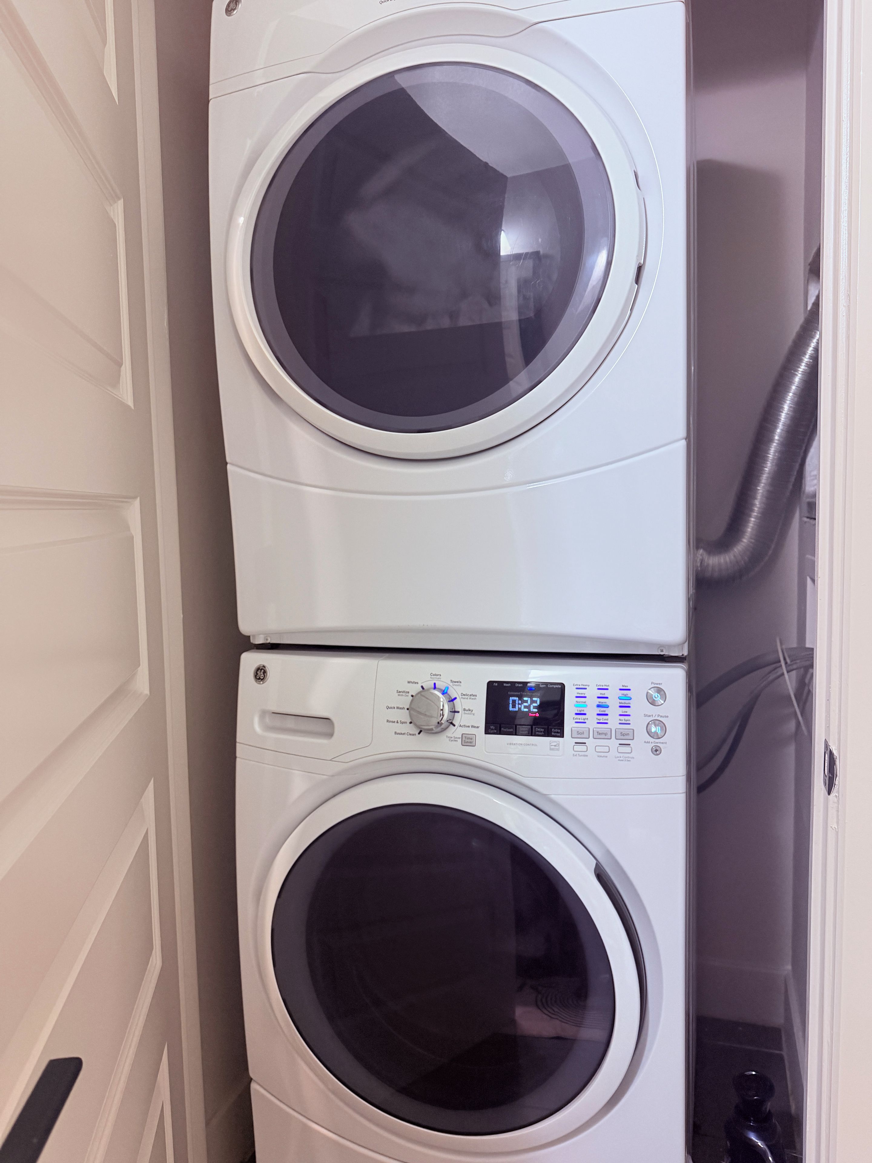 A stacked washer and dryer unit with a control panel displaying settings.