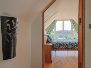 Un dormitorio con cama de madera, una mesita de noche y un ventanal con cortinas.