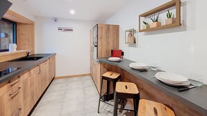 Una cocina moderna con armarios de madera, horno empotrado y una barra con taburetes.