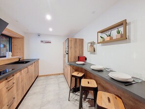 Eine moderne Küche mit Holzausstattung, einem Backofen und einer Bar mit Sitzgelegenheiten.