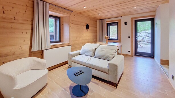 Una habitación acogedora con sofá, una mesa redonda y una ventana con cortinas.