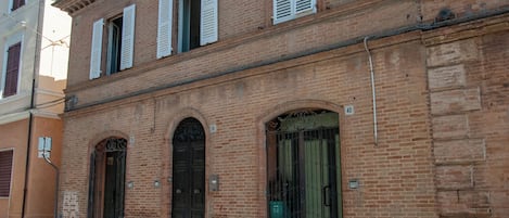 Un edificio in mattoni con tre portici ad arco e una fila di finestre con persiane.