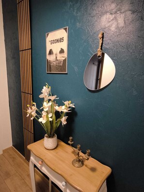 A bathroom with a dark teal wall, a framed poster, a round mirror, a wooden vanity, and a vase with flowers. - Family home in the Poitevin Marshes (Saint-Sigismond)