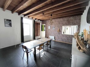 A spacious dining area with a long table and chairs, a brick wall, and a wooden ceiling. - Family home in the Poitevin Marshes (Saint-Sigismond)