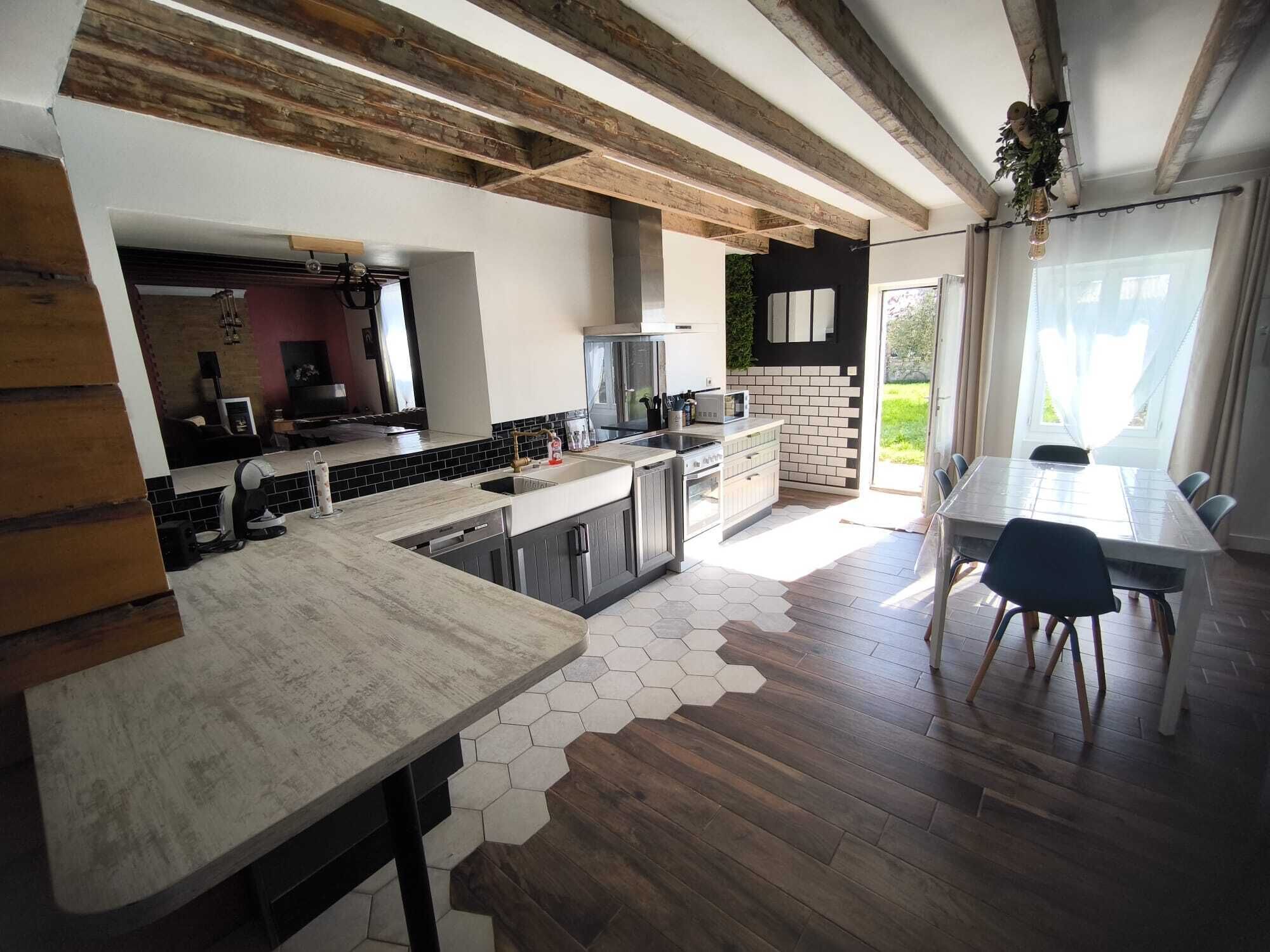 A modern kitchen with a central island, built-in appliances, and a dining area with a table and chairs.