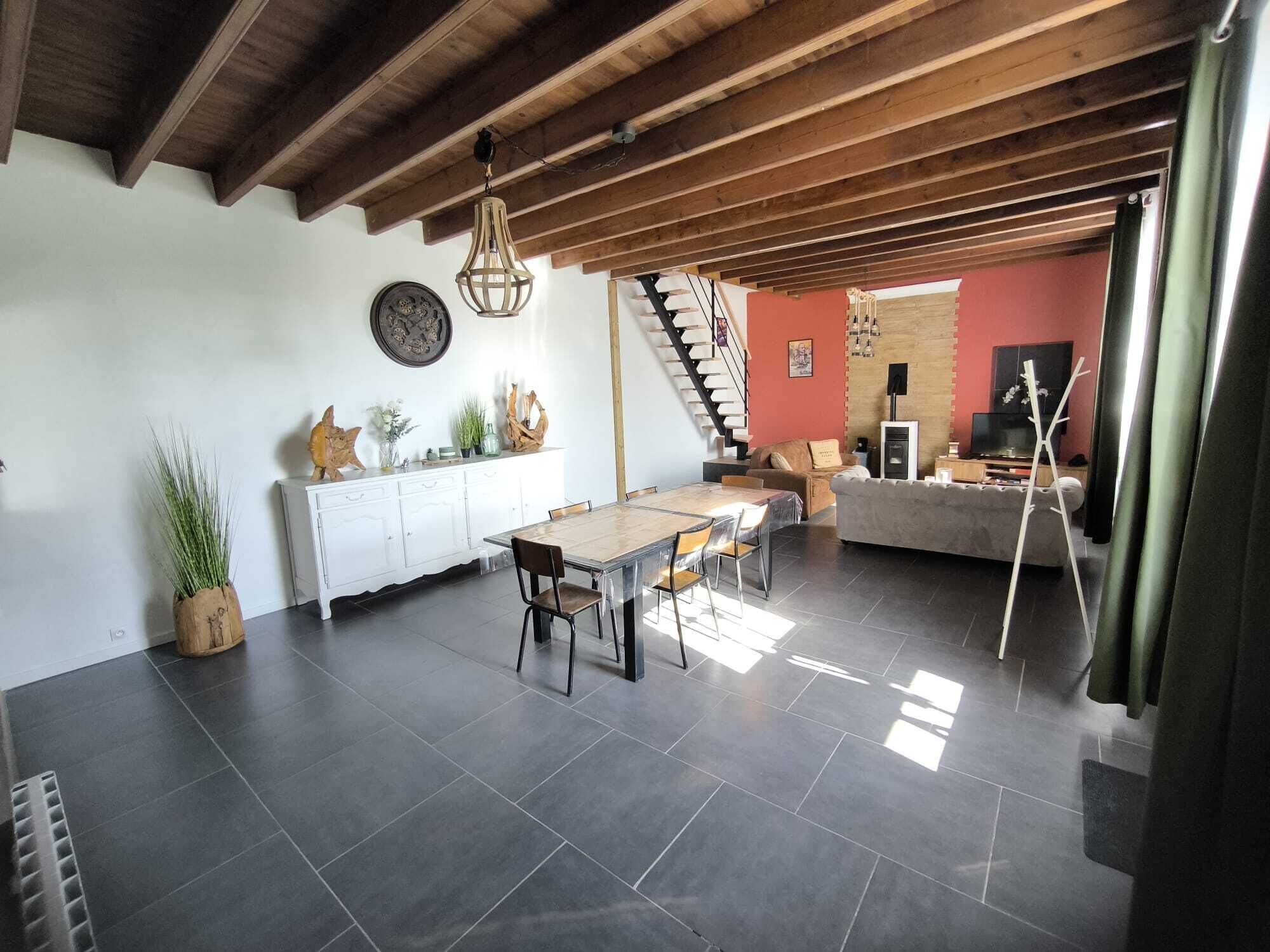 Un espai ampli de sala d'estar amb taula de dinar, sofà i escala que mena a una planta superior.