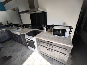 A kitchen with a stove, microwave, and a sink. - Family home in the Poitevin Marshes (Saint-Sigismond)